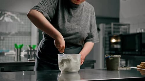 De cerca en una cocina profesional, un panadero saca la mantequilla de maní con una espátula y la mezcla con Wight