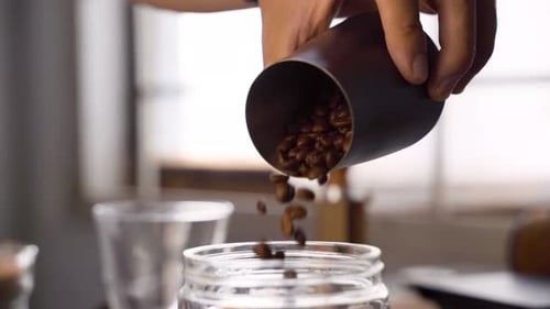 Coffee Beans Being Poured Into Jar