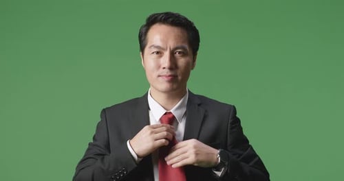 Asian Business Man In Jacket And White Classic Shirt Wearing Red Necktie, Dressing On Green Screen