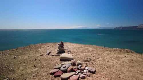 A pyramid of stones against the backdrop of the green waters of the Black Sea and the blue horizon