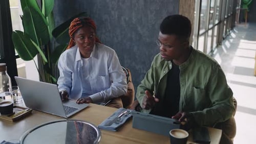 Amidst the Hustle and Bustle of a Cafe Two Black Business Associates One Male and One Female Engage