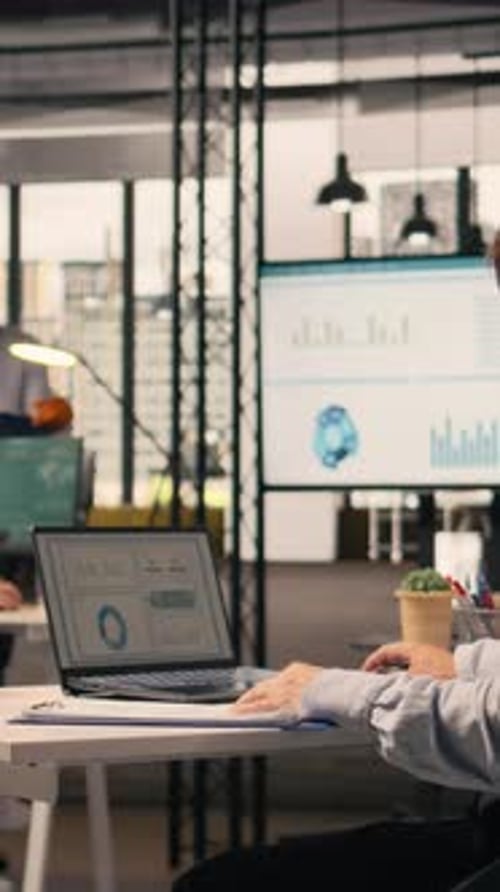 Vertical Video Professional Worker Reviewing Compliance Data on Laptop Screen at Desk