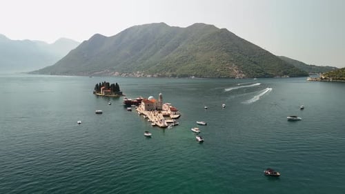 Low aerial slowly circles Our Lady of the Rocks island in Montenegro