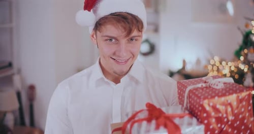 Man in Santa Hat Holding Christmas Gifts