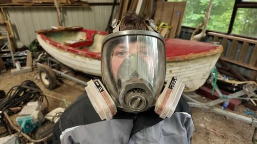 Man Dramatically Removing Full Face Respirator Mask in Workshop