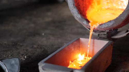 Realtime foundry bucket pouring molten metal into a rectangular cast with flaming sparks in a