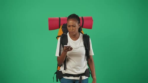 Woman Tourist with Backpack Holding Smartphone Searching for Right Direction Isolated on Green