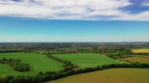Aerial shot of green fields, in the English countryside, on a bright sunny day.