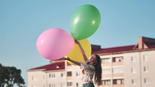 Happy Girl with Big with Colorful Balloons Posing on the Background of City Houses