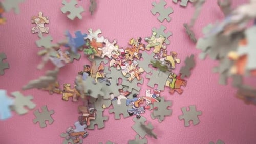 Slow Motion Of Puzzle Pieces Falling On Pink Surface - overhead view