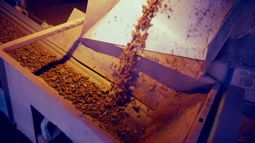 Crumbled clay stones sliding and falling on conveyor belt