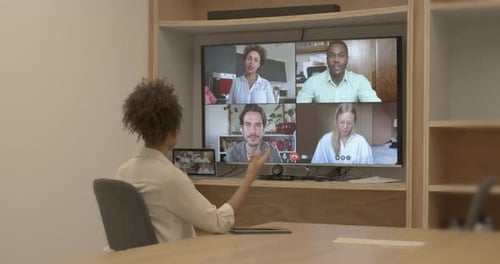 Businesswoman in an office on a video call with coworkers working from home remotely