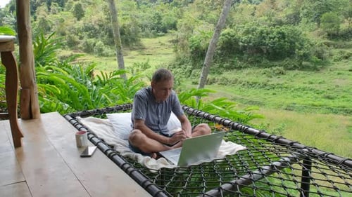 Man Works on Laptop in Tropical Hammock