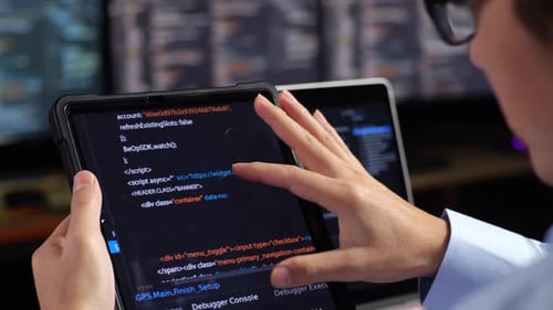 Vista de perto do tablet mostrando o banco de dados sendo verificado por um programador masculino