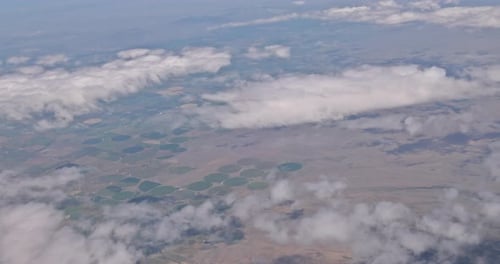 The View of the Land Top From the Window of an Airplane Shows White Clouds of Blue Sky and Beautiful