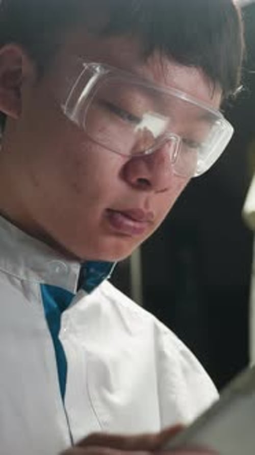 Young Chinese Student Using Tablet in Illuminated Automotive Workshop