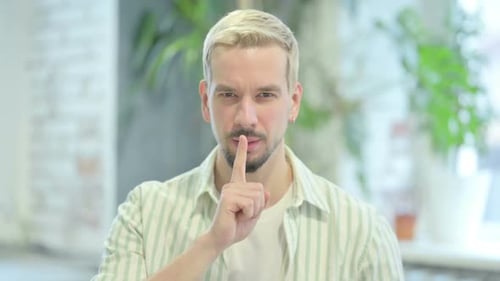 Moderner junger Mann bittet um Stille, Finger auf den Lippen