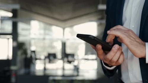 Smiling Mid Aged Business Man Wearing Suit Standing in Office Using Cell Phone