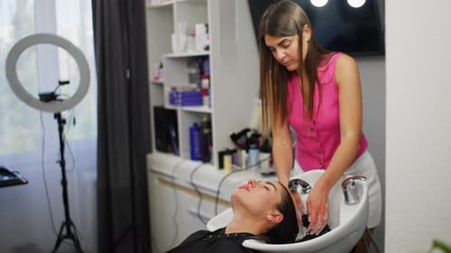 Woman Hairdresser Washing Client's Hair in Salon