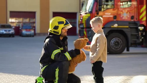 Portrait of Rescued Little Boy with Firefighter Man Standing Near Fire Truck Firefighter in Fire