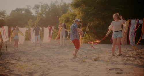 Young Couple Dancing While Friends Grooving at Beach