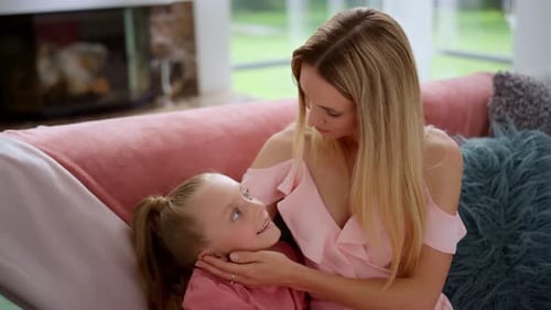 Loving Mother Talking to Daughter on Sofa Indoors