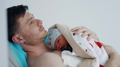 Loving Father Cradles Newborn Infant After Birth