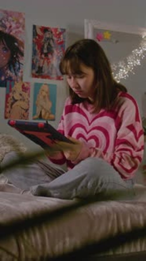 Asian Teenage Girl Using Tablet and Digital Pencil Sitting on the Bed