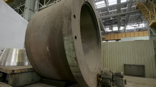 Um enorme componente de maquinário industrial localizado dentro de um estoque de instalações de fabricação em grande escala