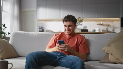 Man Relaxing on Couch Using Mobile Phone