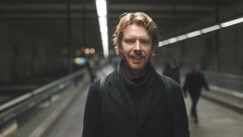 Handsome Smiling Man Standing on Moving Walkway at Airport