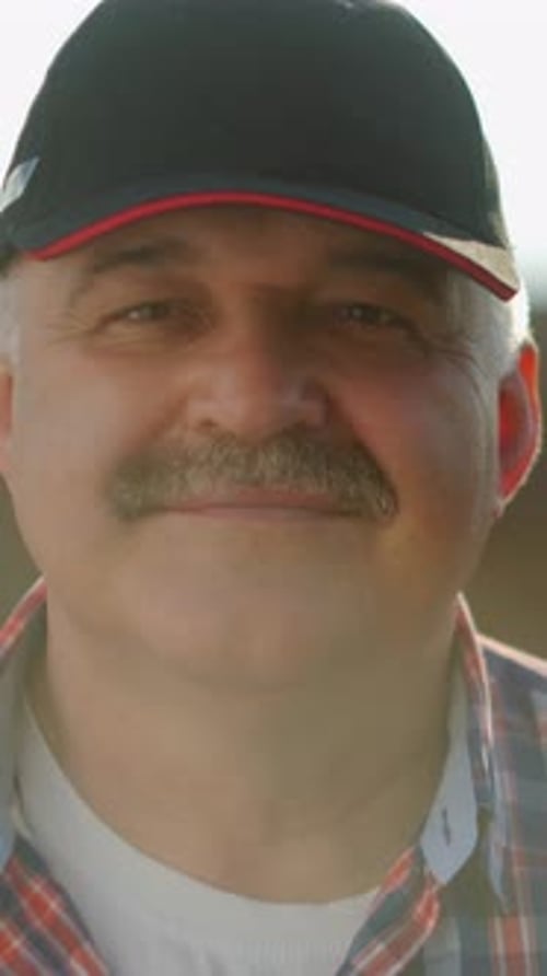 Closeup Transformation of an Older Man in a Cap and Plaid Shirt As His Serious Expression Gradually
