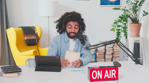 Jovem apresentador de rádio árabe se senta à mesa com microfone no estúdio de gravação