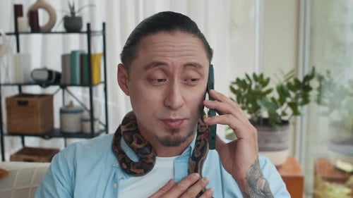 Homme d'affaires multiethnique parlant au téléphone et caressant un serpent enroulé autour du cou