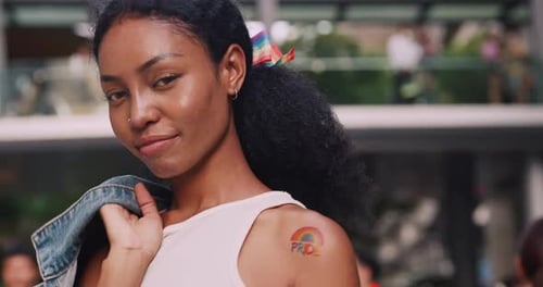 Young black woman with rainbow tattoo stickers and showing symbols of homosexuality in pride parade