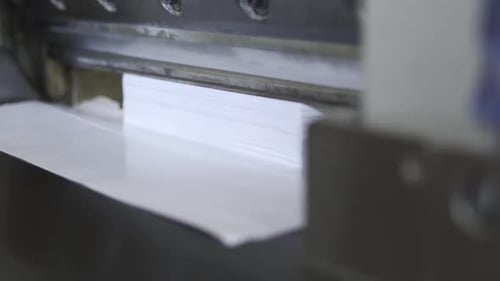 Industrial Paper Cutter Slices Through Stack of White Paper