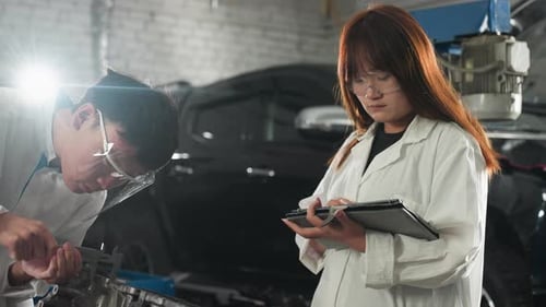 Students Measuring Engine Component and Recording Data in Automotive Workshop