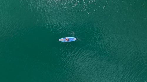 Aerial View Paddleboarding Journey Through a Vast Green Canyon
