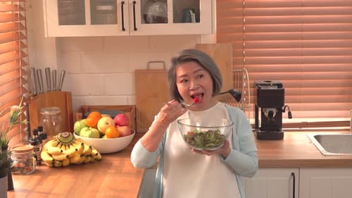 Woman Enjoys Fresh Salad in Sunny Kitchen