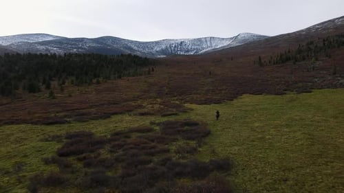 Luftaufnahme eines Mannes auf einem Pferd mit schneebedeckten Bergen im Hintergrund