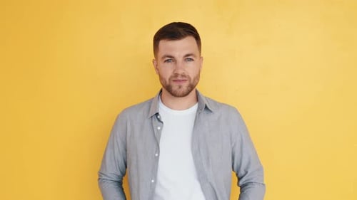 Good mood. Man in casual clothes standing in the studio and showing emotions