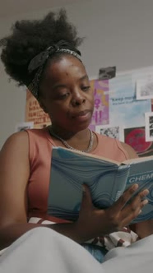 Young Woman Reading Chemistry Textbook in Bed