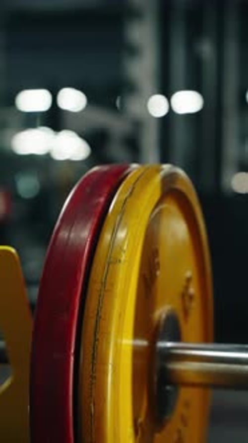 Closeup of a Heavy Barbell Loaded with Yellow and Red Bumper Plates in a Modern Gym Captured with