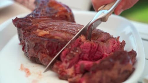 Slicing Ribeye Steak on White Plate Close Up