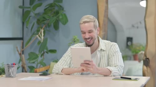 Man Using Tablet for Video Call at Desk
