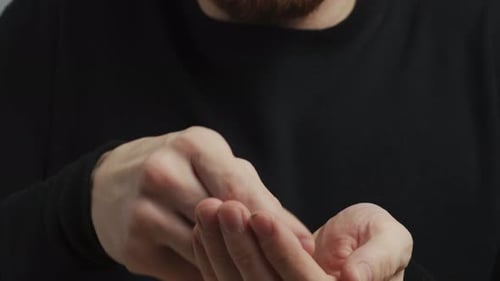A young man in a black sweater and a red beard, drinking a pill, close-up video slide.