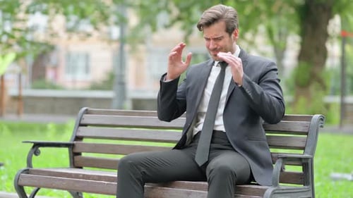 Middle Aged Businessman with Migraine Sitting Outdoor