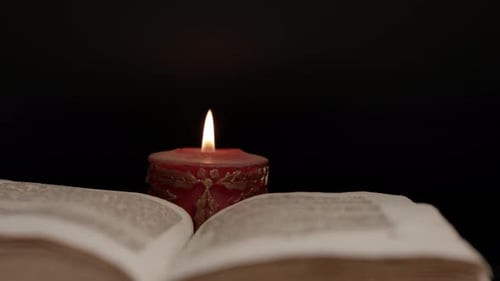 Close up of an open book surrounded by candlelight