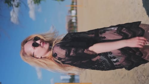 Beautiful, attractive, happy girl posing on a sandy beach on a sunny day wearing a silver swimsuit,