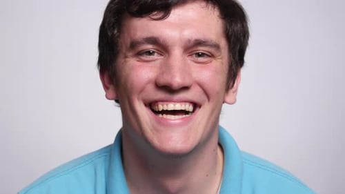 Confident young man smiling in a bright white studio portrait headshot